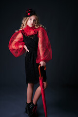 retro portrait of a girl in a black dress with a red collar and an umbrella. vintage hat. studio. dark background
