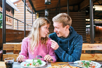 young couple in a cafe feeds each other with a fork