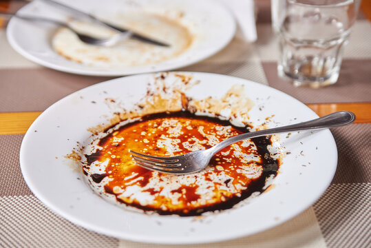 dirty plate and fork in sauce on the table. leftover food