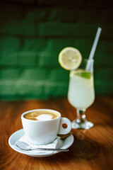 Close-up of cappuccino coffee and lemon juice on the table in a cafe.