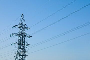 High voltage tower against blue sky on sunny day