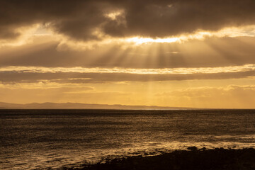 sun beams filtering through cloud by the sea