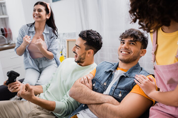 excited hispanic friends showing win gesture while playing video game