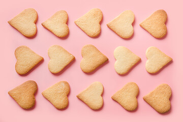 Pattern of homemade traditional heart shaped cookies for Valentine's day on pink background. Top view.