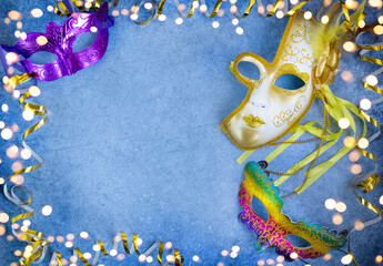 Brazilian or Venetian carnival.A bright multicolored mask close up on a dark background with a Golden serpentine,tinsel and light bokeh from a lantern.holiday.Banner.Flat lay.Top view.Copyspace