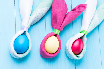 Easter eggs and the shape of rabbit ears, on a blue wooden background, selective focus, tinted image