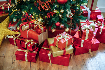 Fototapeta na wymiar Christmas Gifts wrapped in classic red paper, background with xmas lights bokeh of blurred under Christmas tree. Copy space