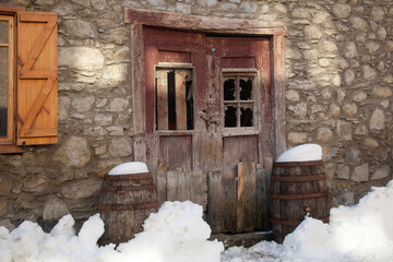 Horizontal shot of the snow in front of the derelict wooden gate of a mountain house flanked by two...