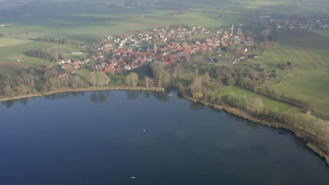 Drone aerial of the typical german village Seeburg located at the Seeburger See on a beautiful Sunday morning. A scenic winter and autumn landscape inviting for a hike with the family in Germany.