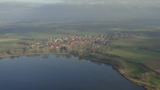 Drone aerial of the typical german village Seeburg located at the Seeburger See on a beautiful Sunday morning. A scenic winter and autumn landscape inviting for a hike with the family in Germany.