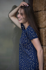 Beautiful young woman laughing near the wall and window outdoors