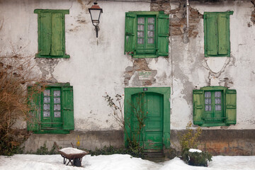 Horizontal shot of an old mountain house façade with its wooden gate and windows painted green on...