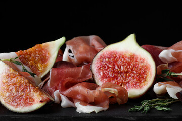 Delicious ripe figs and prosciutto served on slate board, closeup