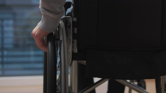 Man on wheelchair at home looking through window. Handicapped invalid paralysed person, depressed alone.