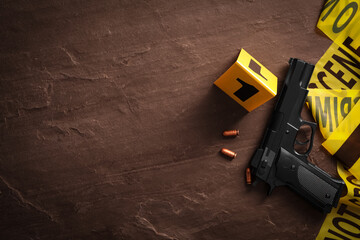 Flat lay composition with gun and bullets on black slate background, space for text. Crime scene