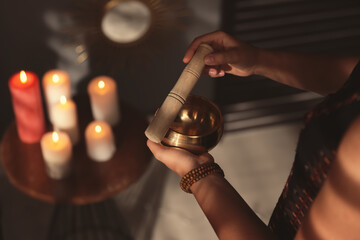 Fototapeta na wymiar Healer using singing bowl in dark room, closeup