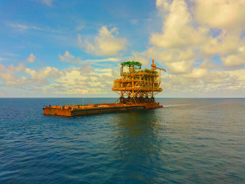 Launch barge towed by tug and loaded with topside. Cargo barge with topside on. 