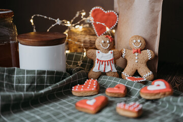 gingerbread cookies in the form of a pair of boy and girl and red hearts lie on a green tablecloth on a wooden table. Valentine's Day.