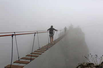 Tourists walk on a suspension bridge in the fog in the Ai-Petri mountains in Crimea