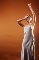 Obraz premium young pretty girl with blond hair in dress posing cheerful on brown background, lifestyle people concept