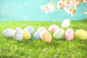 Happy Easter background, spring-time concept. Colorful pastel eggs, nests and bunny toys on  sunny spring day, meadow green grass. Easter greeting card mockup, copy space.