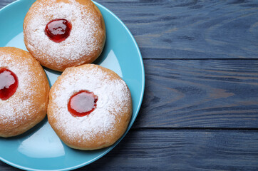 Hanukkah doughnuts with jelly and sugar powder on blue wooden table, top view. Space for text