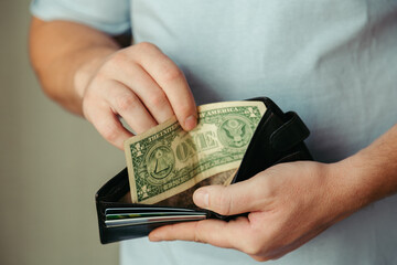 the man's hands take out 1 dollar bills from an empty wallet. Poverty concept, crisis. dismissal or cost savings