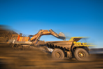 Big yellow dump truck and excavator in coal mine 