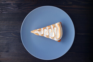 Plate of a Slice of Delicious Lemon Meringue Tart on Black Wooden Background
