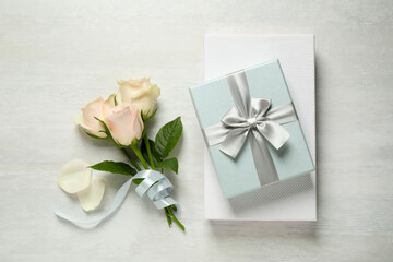 Obraz na płótnie Canvas Elegant gift boxes and beautiful flowers on white table, flat lay
