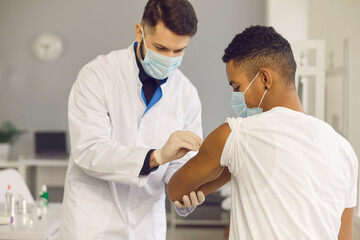 Doctor cleans skin on patient's arm with disinfectant before injecting him with vaccine