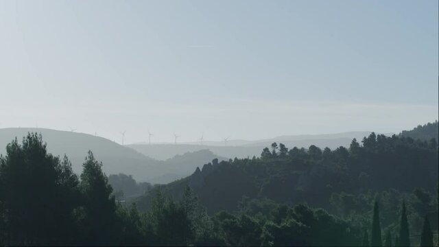 Drone shot flying through the Black mountain of Narbonne during the sunrise with a beautiful light with big windmill farm around