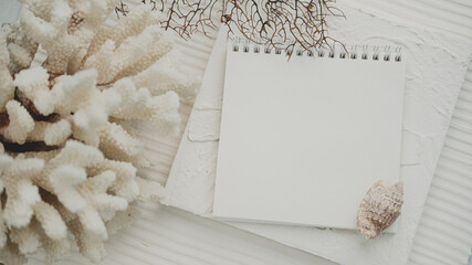 seashells pearls corals on a textured white background . space for text. the view from the top . notepad