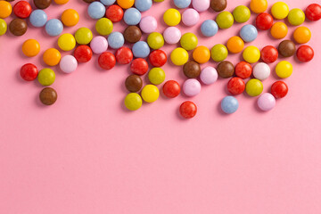 Obraz premium colored sugar coated chocolates on a pink surface.