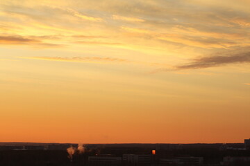 Sun below the horizon and clouds in the fiery dramatic orange sky at sunset or dawn backlit by the...