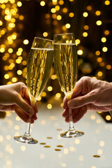 Man and woman hands brings glasses of champagne on festive lights background