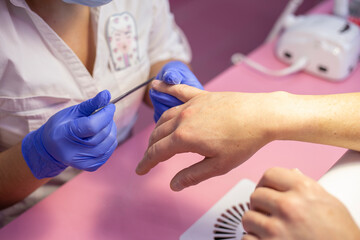 Closeup hands in gloves of a qualified manicurist filing man's nails. Men's manicure in salon