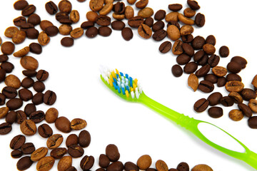 Coffee beans are scattered around the toothbrush. Coffee spoils teeth and makes them yellow. Flat lay, copy space.	