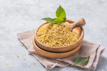 Uncooked bulgur in wooden bowl, rustic style. Bulgur wheat grains. Healthy food