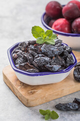 Dried plum or prunus in bowl with fresh plum fruits.