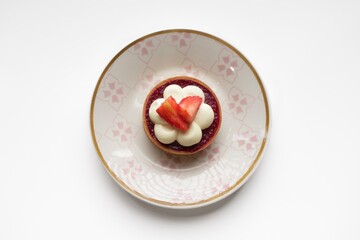 Tart with meringue, raspberry filling and strawberries on a white plate