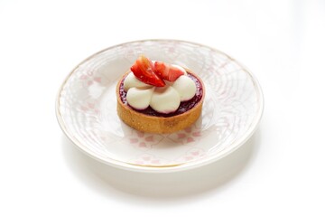 Tart with meringue, raspberry filling and strawberries on a white plate