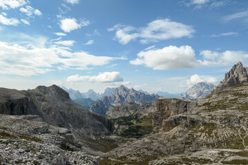 An endless view on a high and desolated mountain peaks in Italian Dolomites. The lower parts of the mountains are overgrown with moss and grass. Raw and unspoiled landscape. Few clouds above the peaks