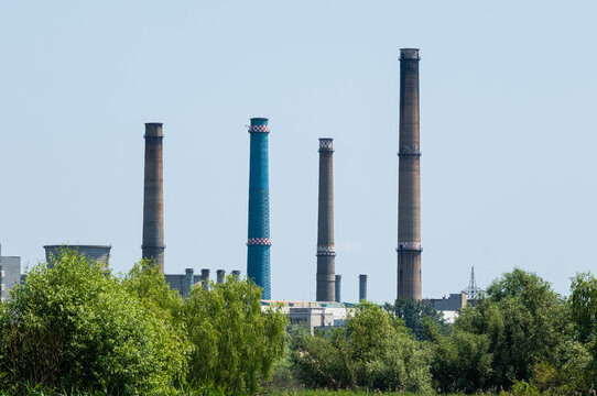 The furnaces of the district heating power plant in Bucharest, seen from the Vacaresti Delta in the middle of the day, among green trees. Delta Vacaresti is a natural park.