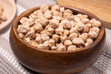 Chickpeas in a wooden bowl on kitchen table. Raw chickpeas close-up