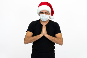 Fototapeta na wymiar Young man wearing a Santa hat. There is a white medical mask. He is wearing a black shirt. Isolated image white background.