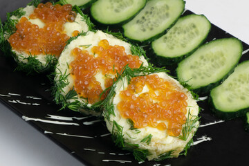 Kanapes with butter and red caviar, and sliced cucumber.