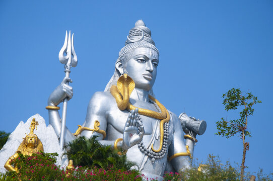 Shot of the beautiful Murudeshwara Temple, a blue statue of a man with a golden snake and a trident