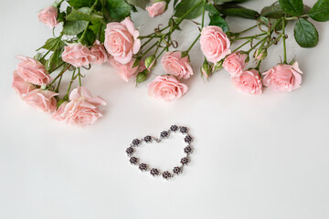 Jeweled heart-shaped bracelet surrounded with pale pink roses. Valentine's day celebrating gift.