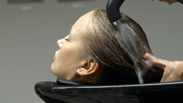 Woman relaxes in hair salon while hair is being washed in sink. Close up. Static shot.